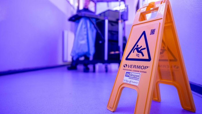 Flur mit einem Hinweisschild, welches davor warnt dass der Boten nass ist und man ausrutschn kann