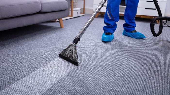 Grauer Teppich, der mit einem Teppichreiniger gereinigt wird